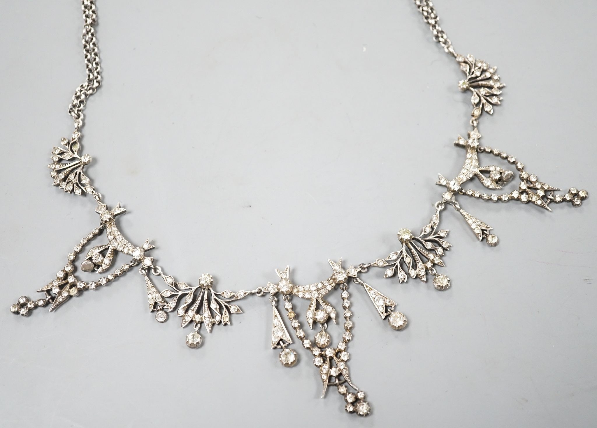 A 19th century white metal and paste set drop necklace, 37.5cm, in an associated gilt tooled fitted leather box.